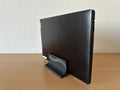 3D printed vertical laptop stand in black holding a closed laptop, side angle