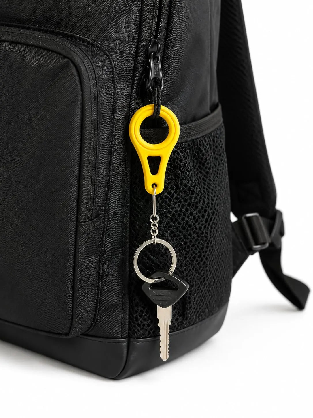 Yellow bag clip keychain on a black backpack strap