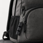 Black 3-key clicky fidget keychain clipped to a grey backpack
