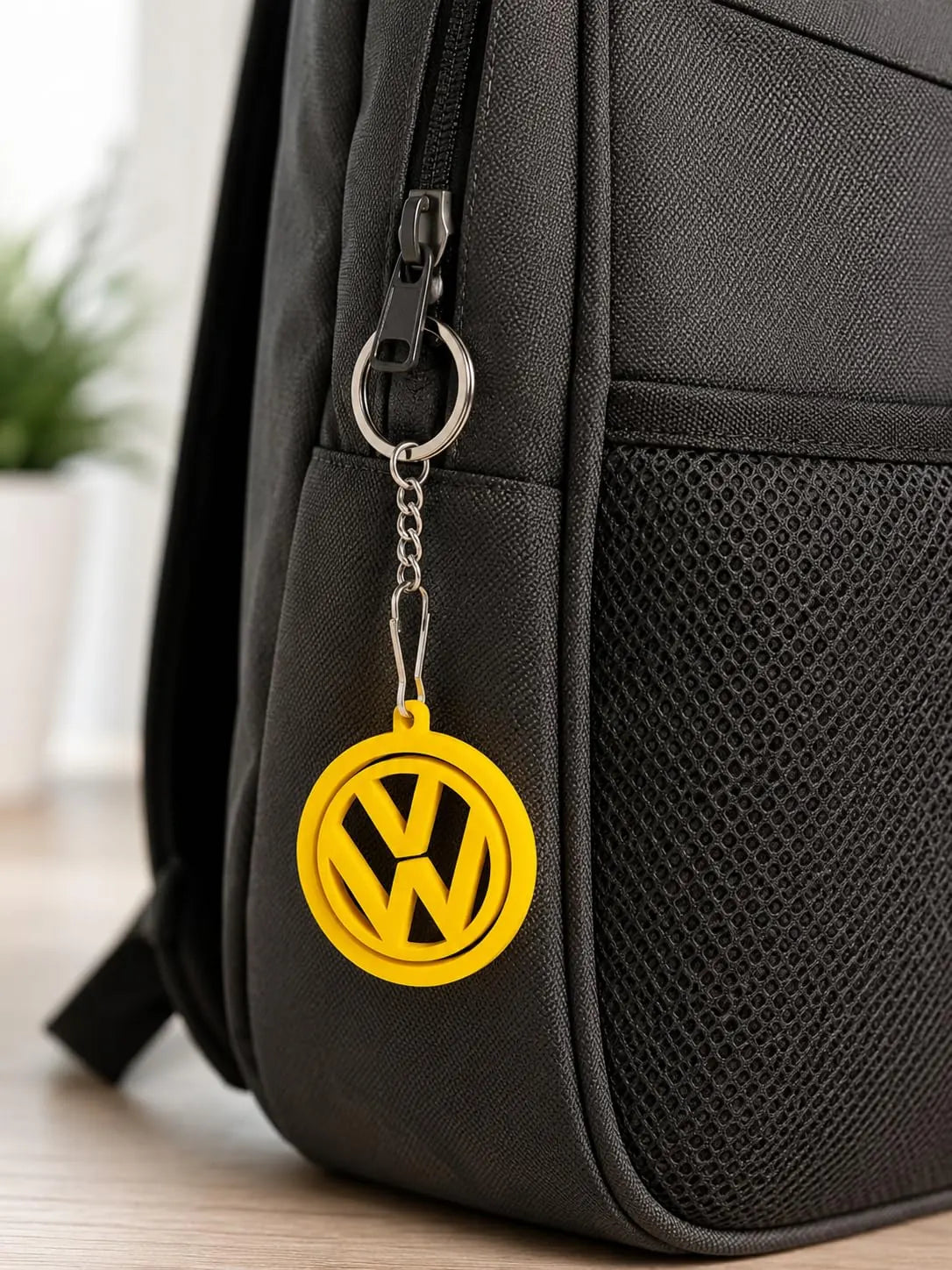 Yellow logo keychain clipped to a black backpack zip