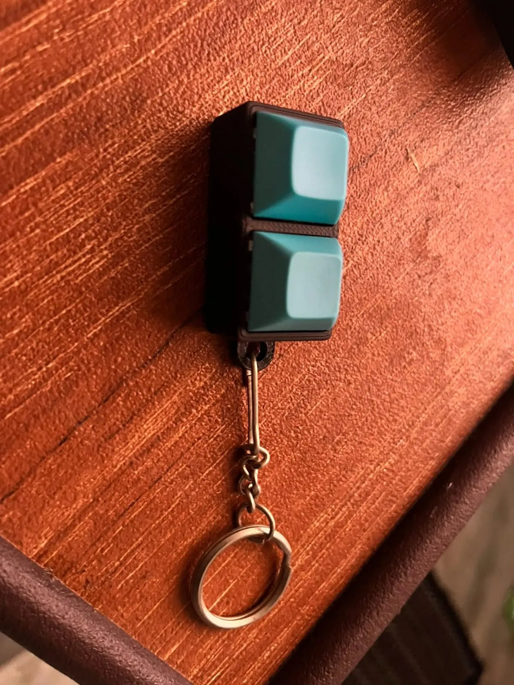 Teal 2-key mechanical keychain close-up on a wooden table