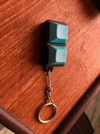 Teal 2-key mechanical keychain close-up on a wooden table