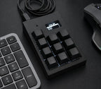 Black PicoPad 3x3+1 with OLED screen next to a keyboard and mouse