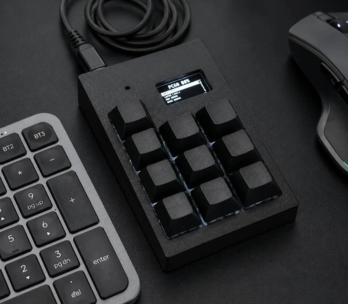 Black PicoPad 3x3+1 with OLED screen next to a keyboard and mouse
